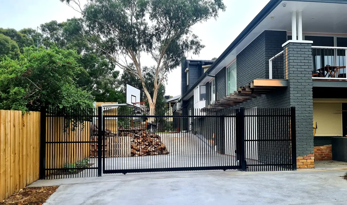 Custom matte black automated driveway gate with matching vertical steel front fencing at a residential property.