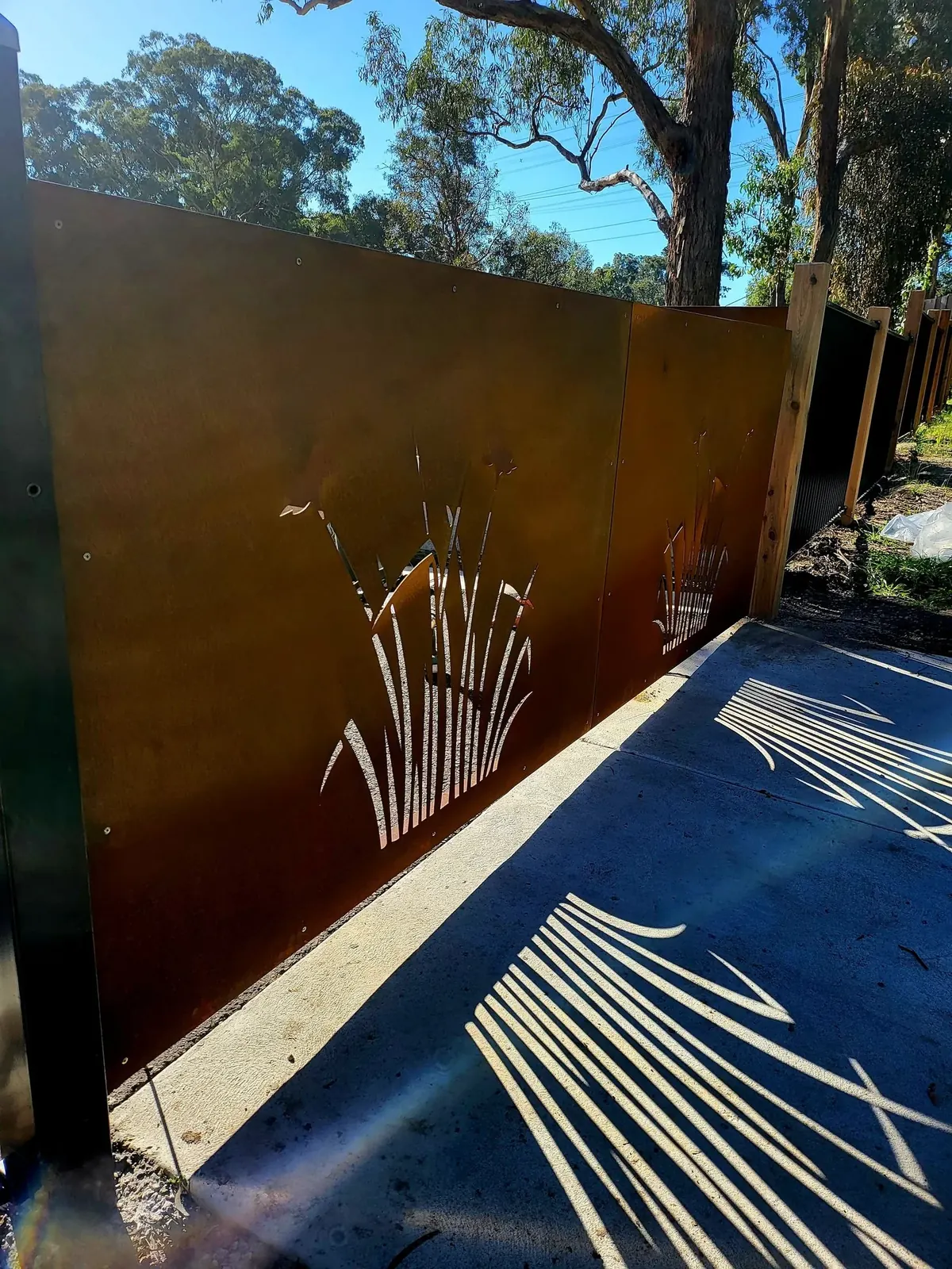 Published project photograph of the laser-cut fencing detail. The gate motor and access controls are not shown.