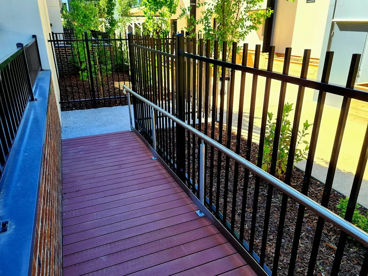 Steel fencing alongside a ramp and landscaped pedestrian route.
